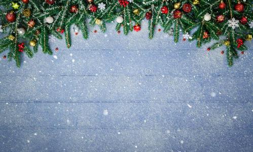 冷杉树枝和圣诞节装饰向下雪的蓝色木材木板