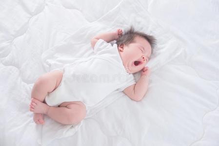 婴儿女孩使人疲乏的白色的身体一套外衣打呵欠向白色的床