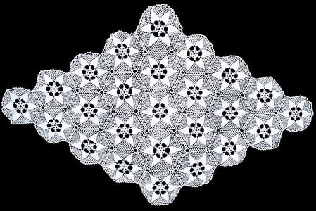 白色的偏菱形蕾丝桌布隔离的向黑的背景摄影图