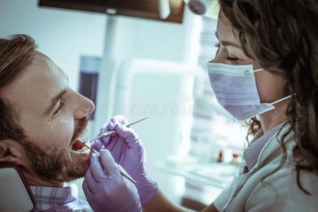 微笑的牙科医生仔细检查微笑的有耐性的.