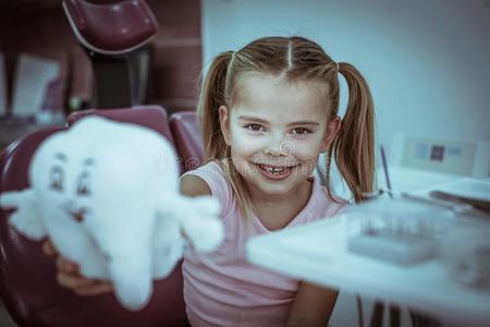 小的女孩在牙科医生办公室使摆姿势和牙玩具.