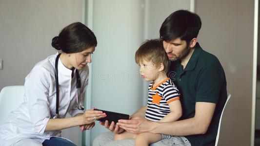 年幼的女人医生讲话和父亲关于小的男孩使用表