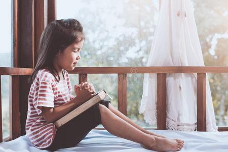 漂亮的亚洲人小的小孩女孩祈祷和折叠的她手