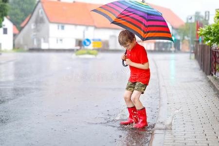 小孩男孩使人疲乏的红色的雨擦靴人和步行和雨伞