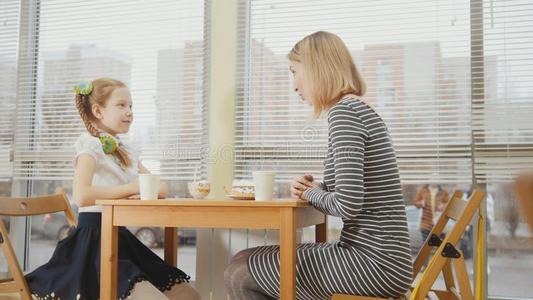 年幼的母亲和女儿是吃caks和喝饮料在指已提到的人波黑