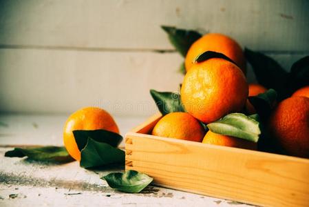 新鲜的橘子采用一老的盒和树叶.向木制的背景