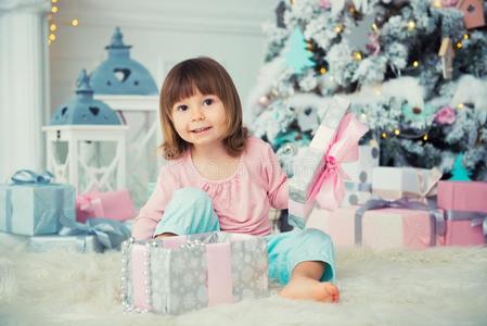 小的婴儿女孩开新的年赠品在近处圣诞节树