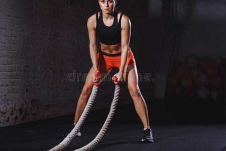 女人训练和与作战粗绳采用十字架适合健身房