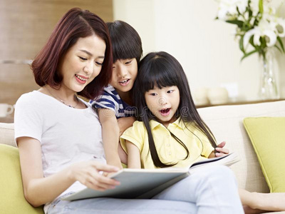 亚洲人母亲阅读故事向两个孩子们
