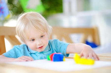 创造性的男孩演奏和富有色彩的造型黏土在幼儿园