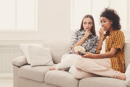 害怕的年幼的女人观察television电视机在家