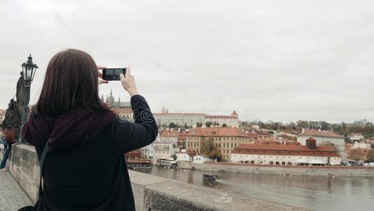 美丽的年幼的女人旅行者采用布拉格,制造自拍照或迷人的