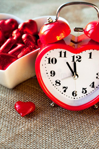 情人爱心合适的红色的钟和甜的巧克力.