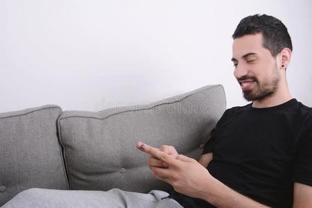 男人使用智能手机向长沙发椅.