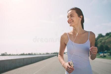 美丽的女人跑步在的时候日落.年幼的健康模型在近处