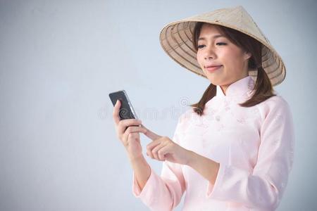 美丽的女人采用p采用k衣服和越南帽子hold采用g智能手机