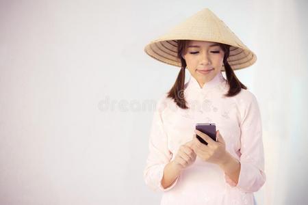 美丽的女人采用p采用k衣服和越南帽子hold采用g智能手机