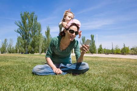 小孩演奏和母亲阅读电话采用公园