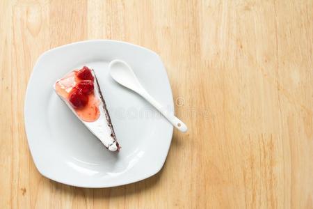 草莓蛋糕和白色的盘子向木材背景