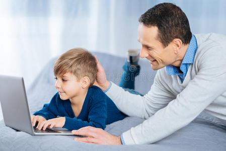 爱的父亲轻拍上端关于他的儿子使用便携式电脑