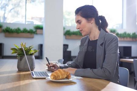 女性的总经理工作的在书桌在期间所有早餐