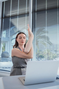 女性的总经理表演的瑜伽在书桌