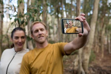 远足者对迷人的自拍照和可移动的电话采用指已提到的人森林