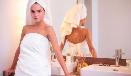 年幼的有魅力的女人起立采用前面关于浴室镜子