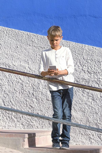 男孩和智能手机起立向楼梯在近处富有色彩的墙