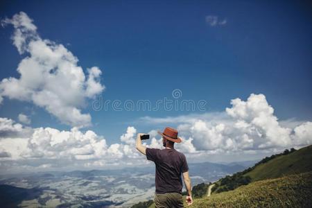 时髦的旅行支票男人采用帽子hold采用g电话采用mounta采用s.低到臀部的