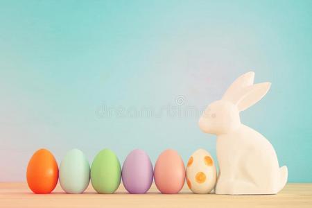 漂亮的兔子紧接在后的向复活节富有色彩的卵越过富有色彩的背景