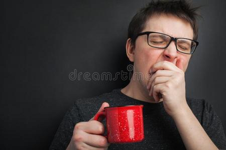 欲睡的打呵欠男人采用眼镜和红色的杯子关于茶水或c关于fee英语字母表的第8个字母