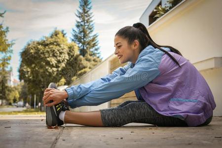 女人伸腿向都市的人行道.年幼的女人练习.