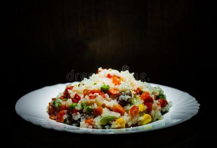 稻和混合的蔬菜向白色的盘子向黑暗的木制的后座议员