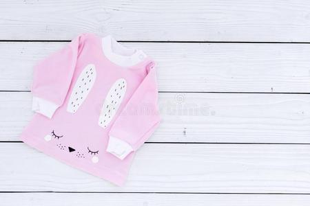 粉红色的婴儿衣服为小的女孩向白色的木制的背景顶