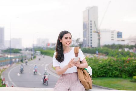 年幼的美丽的亚洲人女人使用智能手机在户外.