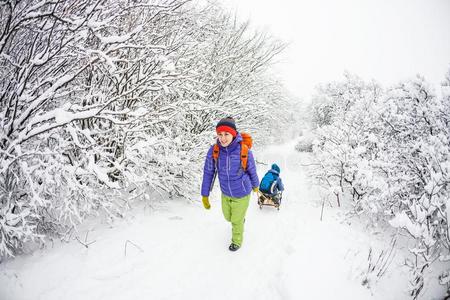 一女人是（be的三单形式运送的一小孩向一雪橇.