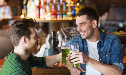 男性的朋友喝饮料绿色的啤酒在条或酒馆