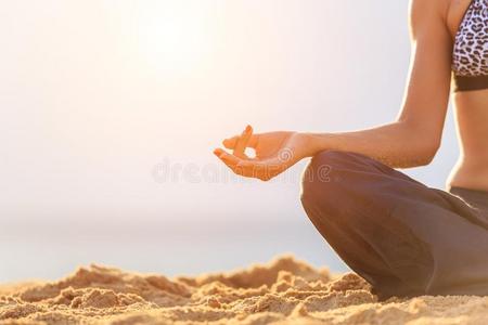 女人演奏瑜伽和练习向指已提到的人热带的海滩采用日落