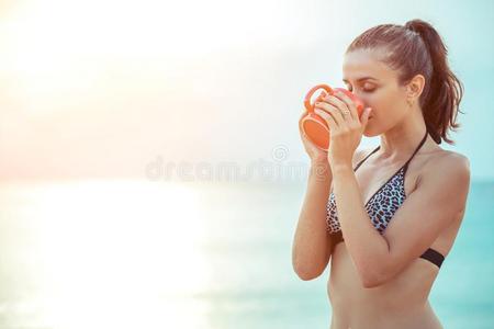 女人喝饮料咖啡豆采用红色的杯子和轻松向指已提到的人热带的海滩