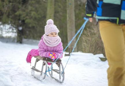 母亲雪撬的使用他的小的女孩向一老的雪橇