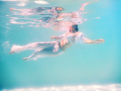 女人美丽的身体游泳在水中的采用白色的衣服