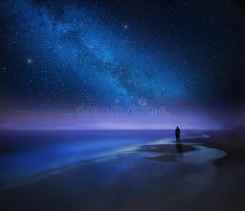 布满星星的夜天越过海和海滩和男人轮廓照片