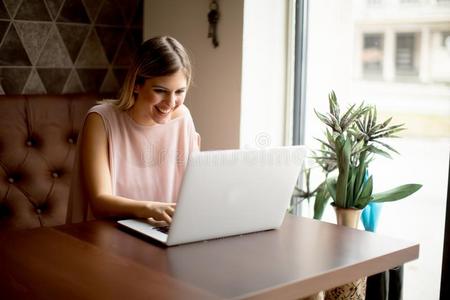 年幼的女人工作的向便携式电脑采用指已提到的人咖啡馆