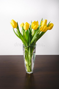 黄色的郁金香采用一v一se向一木制的t一ble一nd白色的w一ll.白色的英语字母表的第3个字母