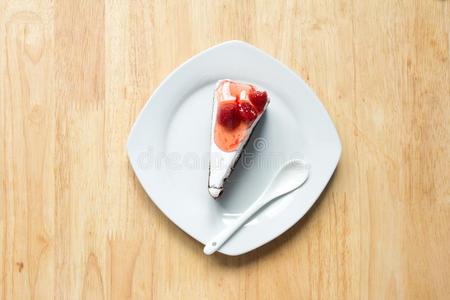 草莓蛋糕和白色的盘子向木材背景