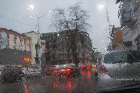 路看法通过汽车窗和雨落下.大街焦外成像光