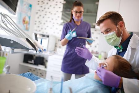 牙科医生使工作向牙齿的诊所和他的助手