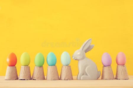 漂亮的兔子紧接在后的向复活节富有色彩的卵越过富有色彩的背景