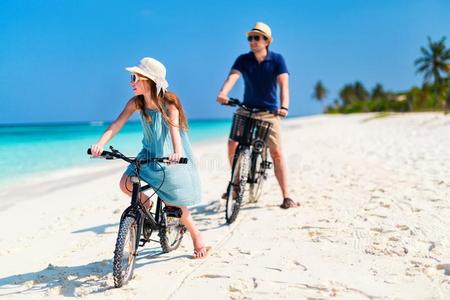 父亲和女儿骑马自行车在热带的海滩